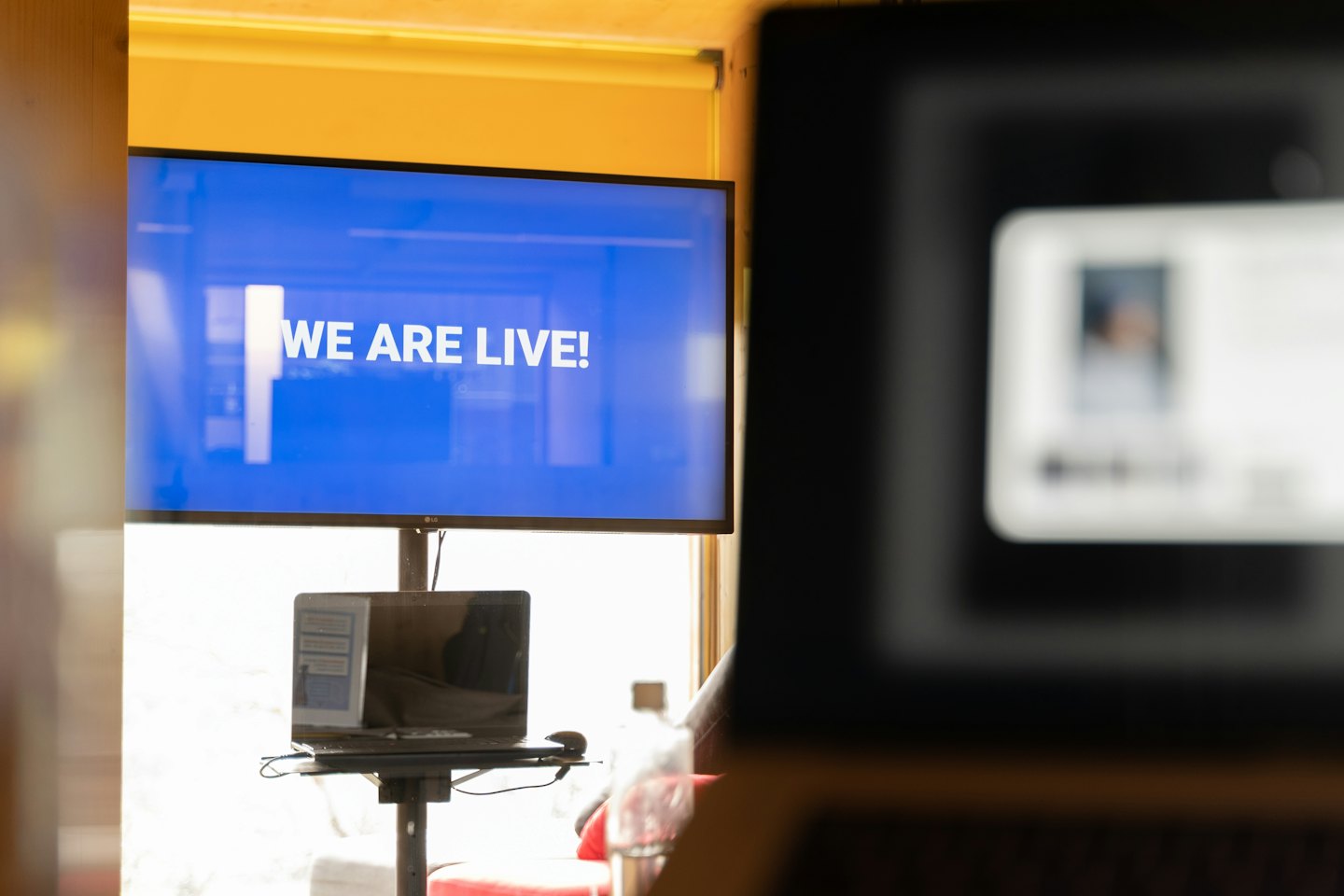Live streaming setup with a large screen showing 'WE ARE LIVE!'.