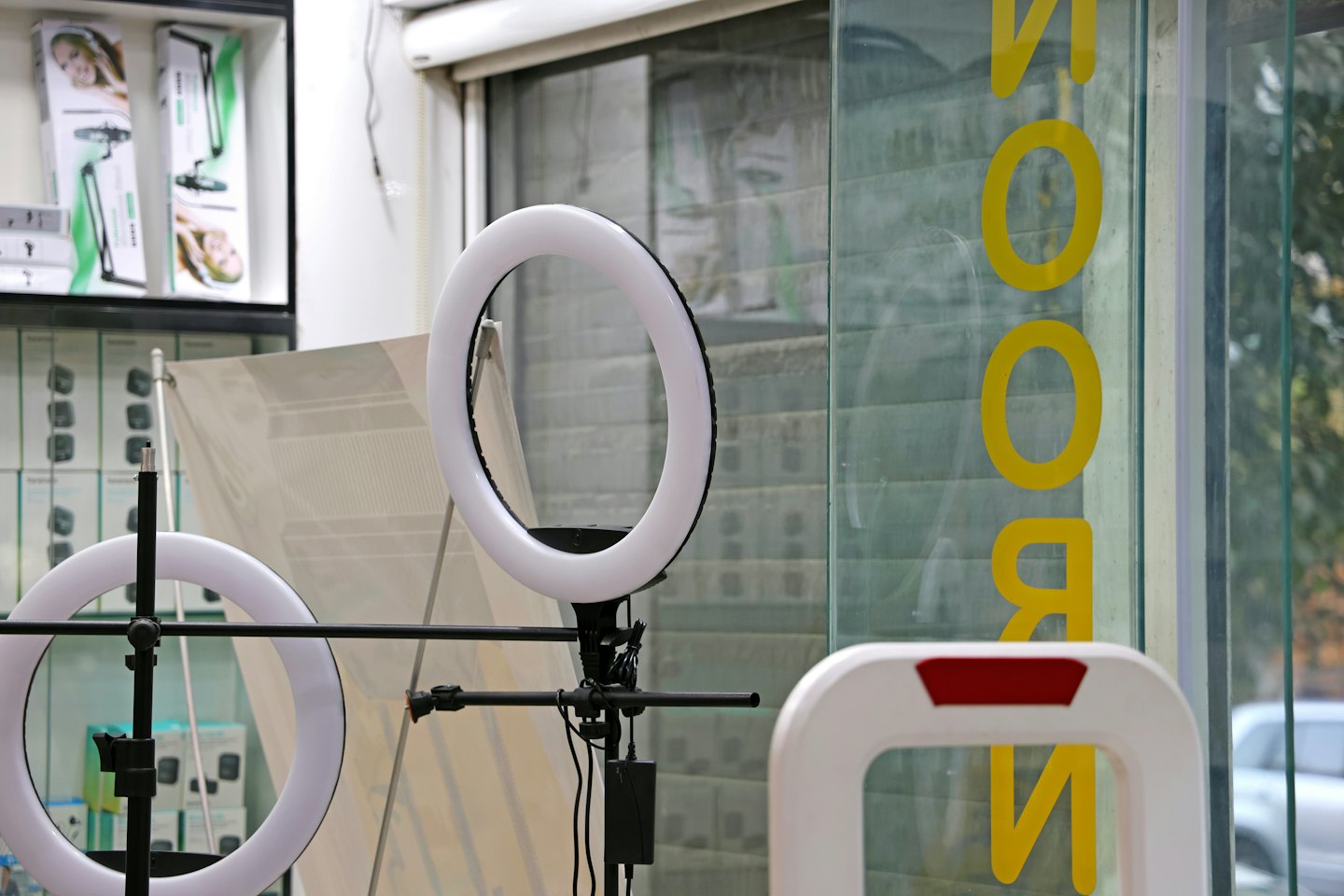 Two illuminated ring lights displayed on shelves in an electronics store.